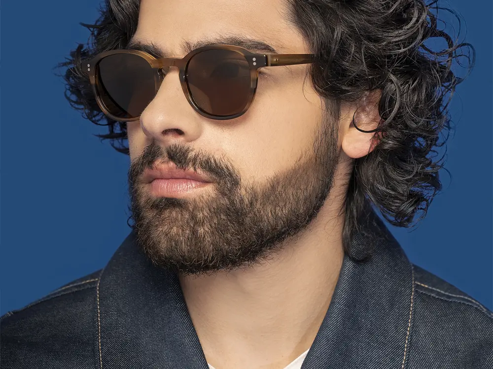 Modelo masculino usando gafas de sol en fotografía publicitaria para campaña de moda y accesorios ópticos.