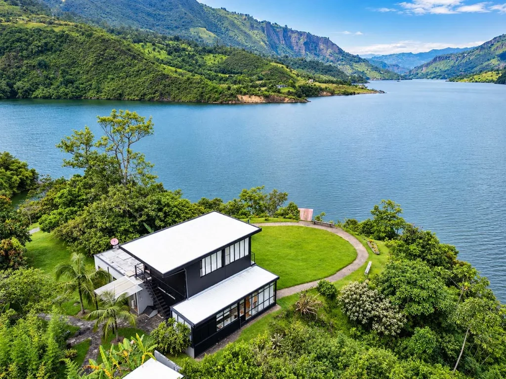 Fotografía aérea con dron de casa moderna junto a lago y montañas